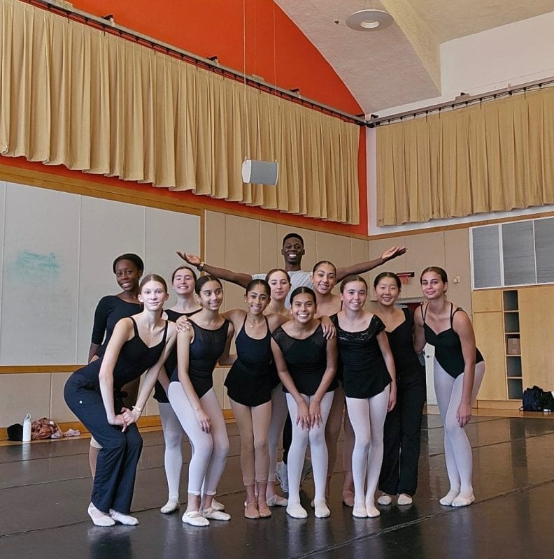 Group of dancers pose for a photo in a ballet studio